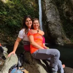 Λάουρα και Λένα μπροστά στον καταρράκτη της Κουνουπίτσας στα Λουτρά Πόζαρ με τα νερά να πέφτουν πίσω τους