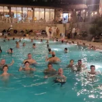 Ομάδα στα θερμά λουτρά Πόζαρ τη νύχτα, με ατμούς και φωτισμένα νερά