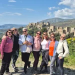 Καλή παρέα, δυνατά χαμόγελα και φόντο που δεν χορταίνεις να κοιτάς. Χαμογελαστή παρέα στη Βάθεια με φόντο το παραδοσιακό χωριό και τη θάλασσα της Μάνης