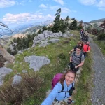 Η ομάδα κινείται σε αλπικό τοπίο με ανοιχτή θέα, σε ένα από τα πιο εντυπωσιακά σημεία της διαδρομής. Ομάδα πεζοπόρων σε ορεινό μονοπάτι της Δίρφυς με πανοραμική θέα στο βουνό και την Εύβοια