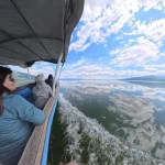 Η βάρκα γλιστρά πάνω στα ήρεμα νερά της Κερκίνης, με τον ουρανό να καθρεφτίζεται εντυπωσιακά στην επιφάνεια της λίμνης. Βαρκάδα στη Λίμνη Κερκίνη με αντανάκλαση του ουρανού στα ήρεμα νερά
