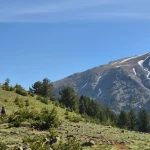 Η μεγάλη ημέρα της ανάβασης ξεκινά, με την πυραμιδοειδή κορυφή του Σμόλικα να κυριαρχεί μπροστά μας. Ορειβατική ομάδα ανηφορίζει προς τη Δρακόλιμνη Σμόλικα με φόντο την κορυφή