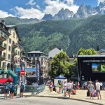 Στην καρδιά του Chamonix, όλα κινούνται. Η αψίδα τερματισμού του Μαραθωνίου του Chamonix στην κεντρική πλατεία, με κόσμο, ιστορικά κτίρια και τις αλπικές κορυφές στο βάθος.