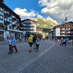 Απογευματινή βόλτα στην Cortina d’Ampezzo κεντρικός δρόμος στην Cortina d’Ampezzo με κόσμο, παραδοσιακά κτίρια και βραχώδη κορυφή στο βάθος