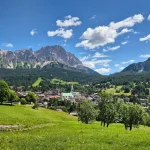 Η Cortina d’Ampezzo μέσα στο πράσινο πανοραμική θέα στην Cortina d’Ampezzo με καταπράσινα λιβάδια, την πόλη και τις βραχώδεις κορυφές των Δολομιτών στο βάθος