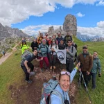 Όλη η ομάδα στο Cinque Torri η ομάδα ποζάρει με τη σημαία του BackpackOnGreece στο Cinque Torri, ανάμεσα σε πράσινες πλαγιές και χαρακτηριστικούς βραχώδεις πύργους
