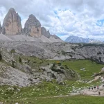 Στο μονοπάτι κάτω από τις Tre Cime πεζοπόροι ακολουθούν το μονοπάτι κάτω από τις Tre Cime di Lavaredo, ανάμεσα σε βραχώδεις πλαγιές και ανοιχτό αλπικό τοπίο