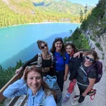 Χαμόγελα πάνω από τη Lago di Braies πέντε μέλη της ομάδας ποζάρουν χαμογελαστά στο μονοπάτι πάνω από τη Lago di Braies, με τα γαλαζοπράσινα νερά στο βάθος