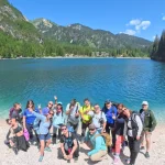 Όλη η ομάδα στη Lago di Braies η ομάδα ποζάρει χαμογελαστή στην όχθη της Lago di Braies, με τα γαλαζοπράσινα νερά και τις δασωμένες πλαγιές στο βάθος