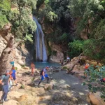 Η παρέα έφτασε στον καταρράκτη Η ομάδα δίπλα στη φυσική βάθρα και τον καταρράκτη, ανάμεσα σε βράχια και πυκνή βλάστηση